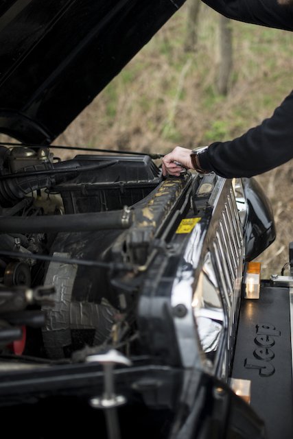 Man taking a look under the hood of a cross country vehicle